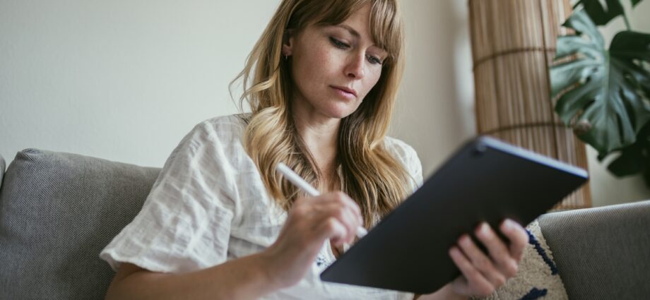 Woman using a stylus writing on a digital tablet